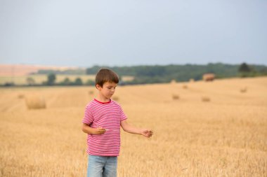 Şirin okul öncesi çocuk, bulutlu bir gün alanında acelack üzerinde oturan
