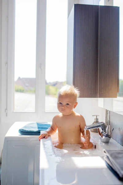 Baby kąpieli w zlewu. Dzieci bawią się pianką i mydłem baniek — Zdjęcie stockowe