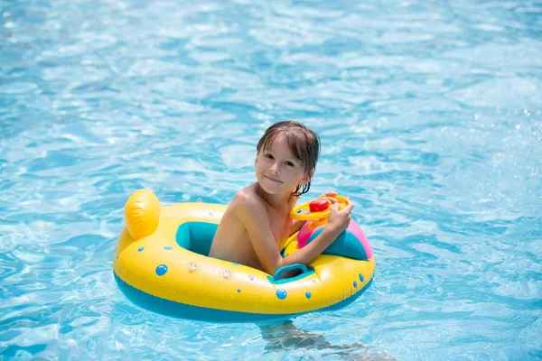 Cute child, playing with inflatable boat in pool — Stock Photo, Image