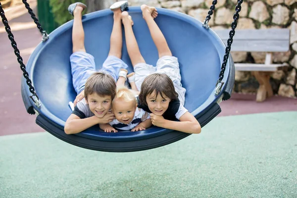 Niño pequeño, niño pequeño, balanceándose en un columpio en el parque — Foto de Stock