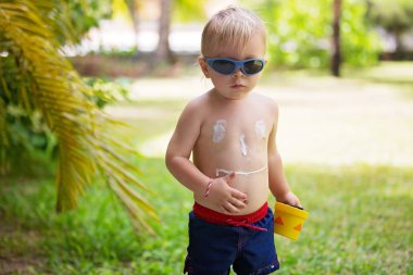 Onun sırtında gülümseme şeklinde güneşten losyon ile çocuk, t gidiyor
