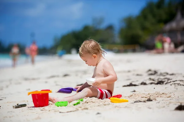 Lindo bebé jugando con juguetes de playa en la playa tropical — Foto de Stock