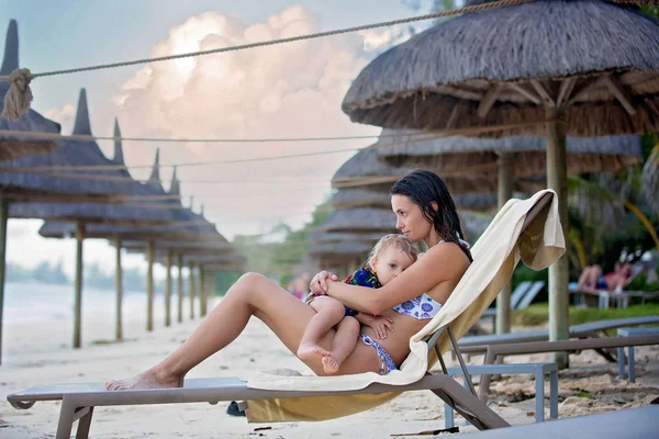 Matka, karmienie piersią jej chłopiec maluch na plaży, przytulanie na t — Zdjęcie stockowe