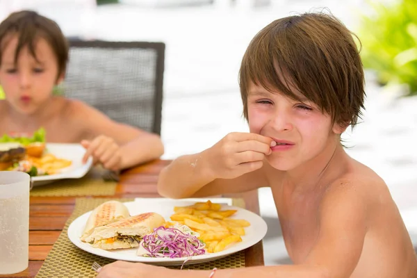 Dolce bambino in età prescolare, mangiare hamburger fresco in un ristorante su b — Foto Stock