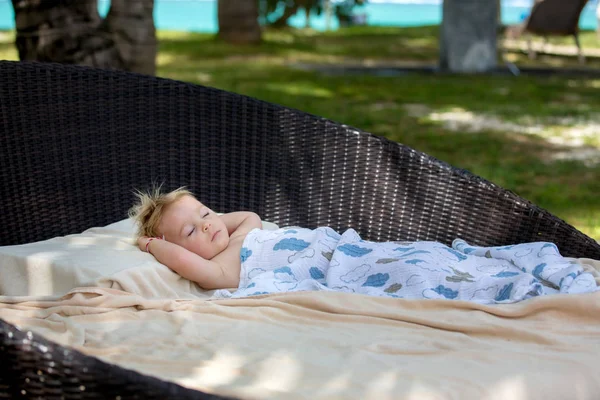 Schattige blonde peuter jongen, slapen op een grote ronde strandstoel op t — Stockfoto