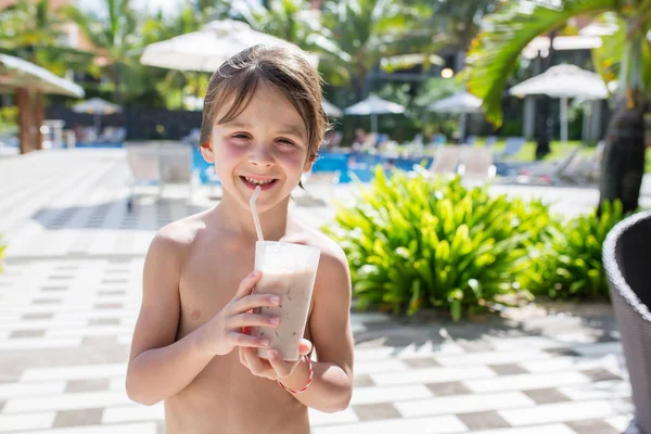 Χαριτωμένο αγόρι, πίνοντας μιλκ σέικ μιλκσέικ στο κατάστρωμα της πισίνας, ενώ σε — Φωτογραφία Αρχείου