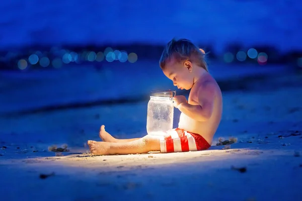 月の上の日没後にビーチに座っている小さな幼児の少年 — ストック写真