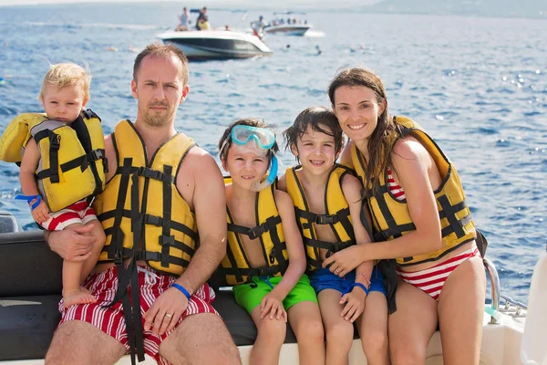 Familia feliz con chalecos salvavidas, divertirse en un viaje en barco mientras está en — Foto de Stock