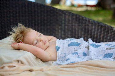 Sevimli sarışın yürümeye başlayan çocuk, t büyük bir yuvarlak plaj sandalyede uyku