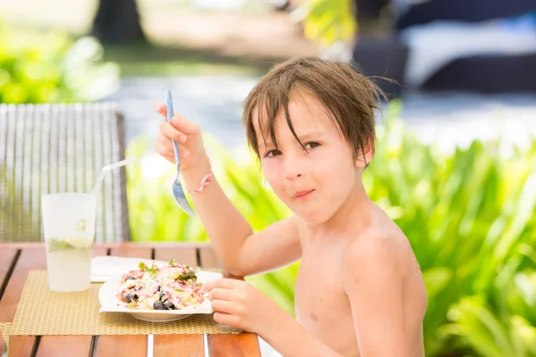 Солодкий дошкільний хлопчик, їсть свіжий салат у ресторані на пляжі — стокове фото