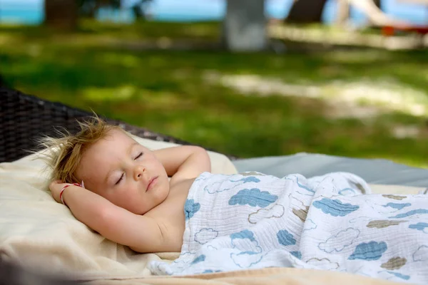 Cute blond chłopiec maluch, spanie na dużym okrągłym fotelu na plaży t — Zdjęcie stockowe