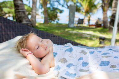 Sevimli sarışın yürümeye başlayan çocuk, t büyük bir yuvarlak plaj sandalyede uyku