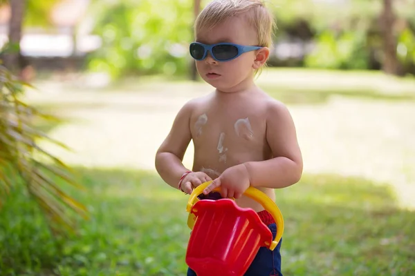 Child with suntan lotion shaped as smile on his back, going at t — Stock Photo, Image