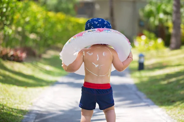Παιδί με αντηλιακή λοσιόν σε σχήμα χαμογελαστή στην πλάτη του, πηγαίνοντας στο t — Φωτογραφία Αρχείου