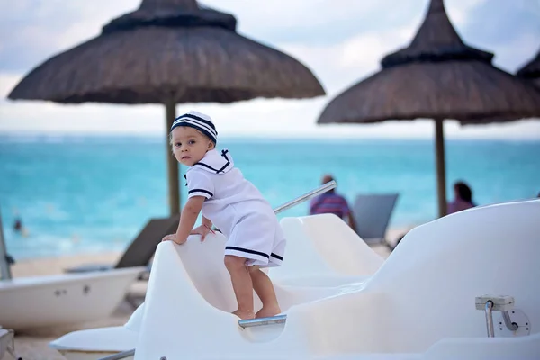 Piękny chłopiec malucha, ubrany jak marynarz, grając na plaży — Zdjęcie stockowe