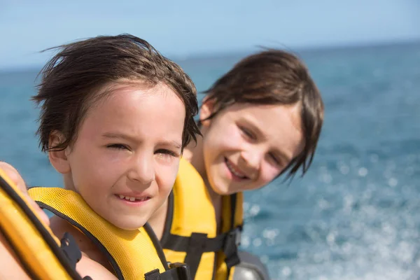 Familia feliz con chalecos salvavidas, divertirse en un viaje en barco mientras está en — Foto de Stock