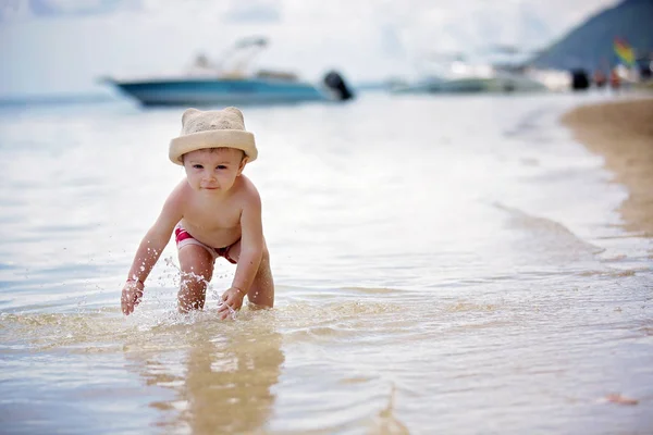 Dulce niño, jugando en aguas poco profundas en una playa tropical — Foto de Stock