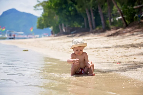 Dulce niño, jugando en aguas poco profundas en una playa tropical — Foto de Stock