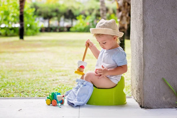 Zoete peuter jongen, zittend op potje op een achterporch in een vakantie — Stockfoto