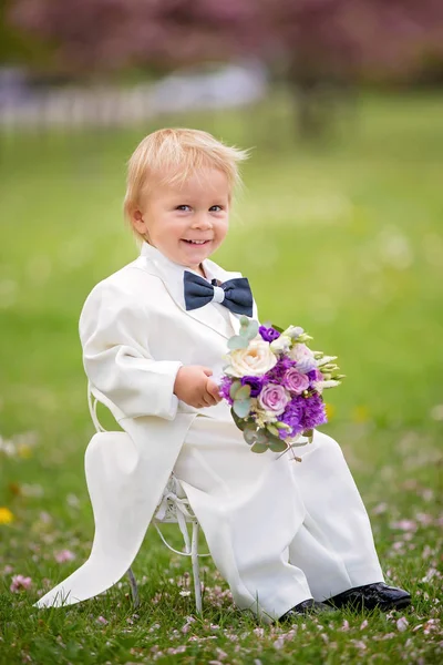 Hermoso niño, vestido con esmoquin blanco, sosteniendo hermosa —  Fotos de Stock