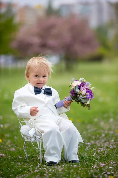 Hermoso niño, vestido con esmoquin blanco, sosteniendo hermosa — Foto de Stock