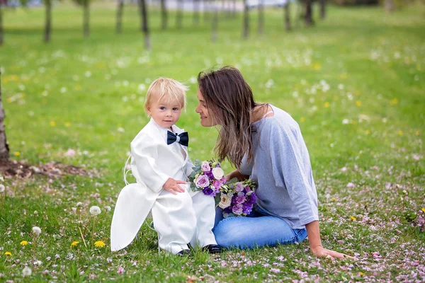 Beautiful toddler boy, dressed in white tuxedo, holding gorgeous — Stock Photo, Image