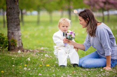 Güzel yürümeye başlayan çocuk, beyaz smokin giymiş, muhteşem tutarak