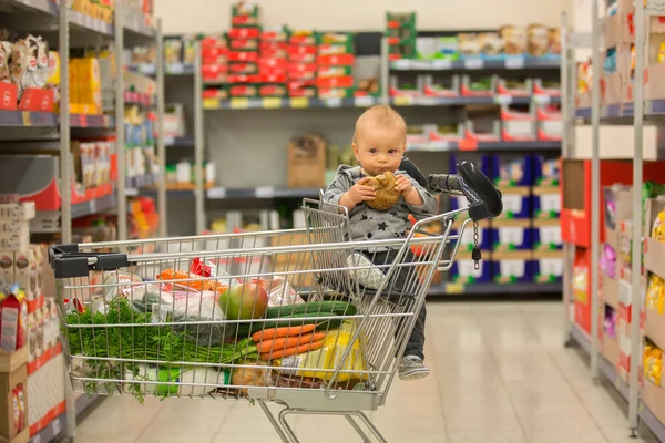 Menino bebê, sentado em um carrinho de compras na mercearia, s — Fotografia de Stock