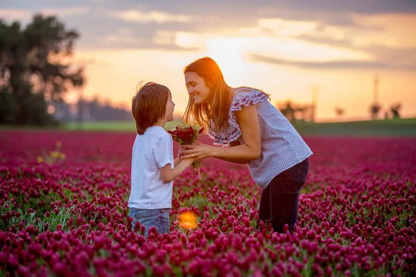 Beautiful mother and son in crimson clover field, mom getting bo
