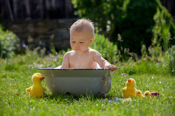 Bonito menino criança em uma bacia, tomando um banho no jardim com — Fotografia de Stock