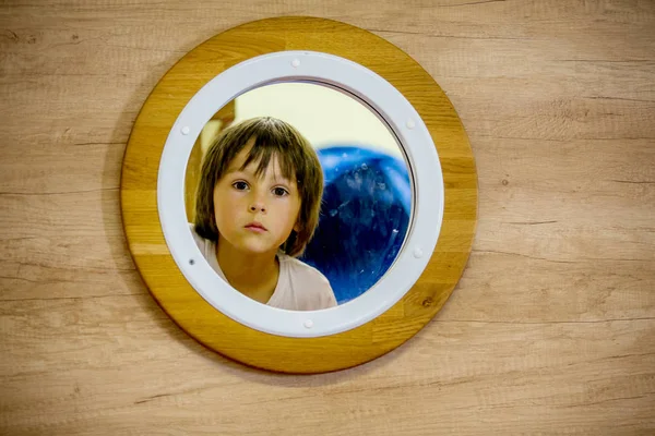 Triste niño, mirando a través de la ventana redonda de un submari — Foto de Stock