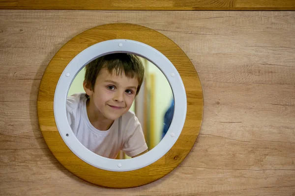 Trauriger kleiner Junge, der durch das kleine runde Fenster eines U-Boots blickt — Stockfoto