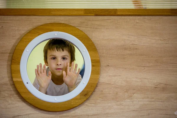Üzgün küçük çocuk, bir submari küçük yuvarlak pencereden bakarak — Stok fotoğraf