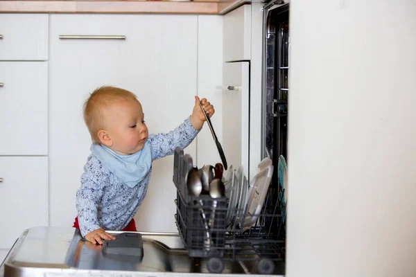 幼児の子供、男の子、お母さんを助け、皿洗いで汚れた皿を入れて — ストック写真