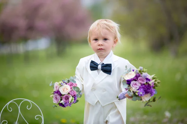 Hermoso niño, vestido con esmoquin blanco, sosteniendo hermosa — Foto de Stock