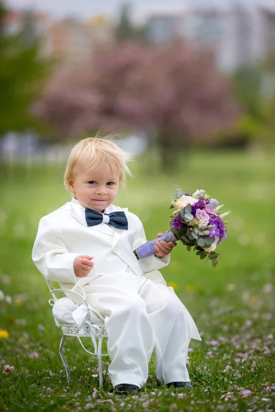 Hermoso niño, vestido con esmoquin blanco, sosteniendo hermosa — Foto de Stock
