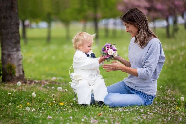 Beautiful toddler boy, dressed in white tuxedo, holding gorgeous — Stock Photo, Image