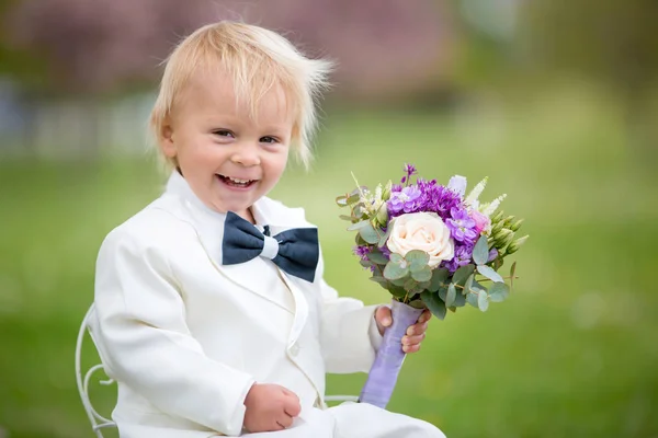 Beautiful toddler boy, dressed in white tuxedo, holding gorgeous — Stock Photo, Image