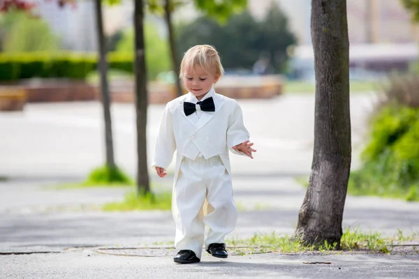 Красивый мальчик в смокинге, играет в парке на свадьбе — стоковое фото