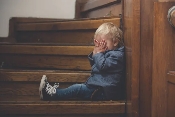 Criança triste, sentado em uma escada em uma casa grande, conceito para bu — Fotografia de Stock