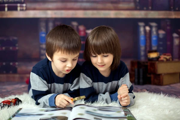 Deux petits enfants, garçons, lisant un livre avec loupe — Photo