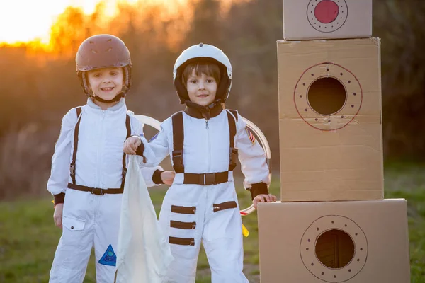 Zwei entzückende Kinder, die im Park bei Sonnenuntergang spielen, angezogen wie ein — Stockfoto