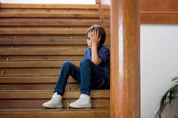 Niño triste, sentado en una escalera en una casa grande, concepto para bu —  Fotos de Stock