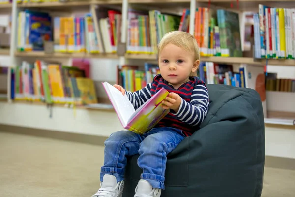 Smart todller boy, educating himself in a library, reading books — Stock Photo, Image