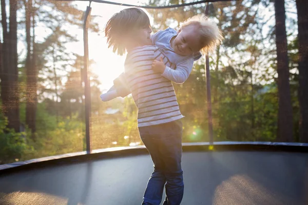 Słodki preteen chłopiec i jego brat maluch skakanie na trampoliny. — Zdjęcie stockowe