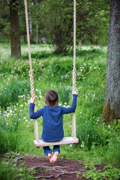 Doux enfant, garçon préadolescent, balançant sur une balançoire en bois — Photo