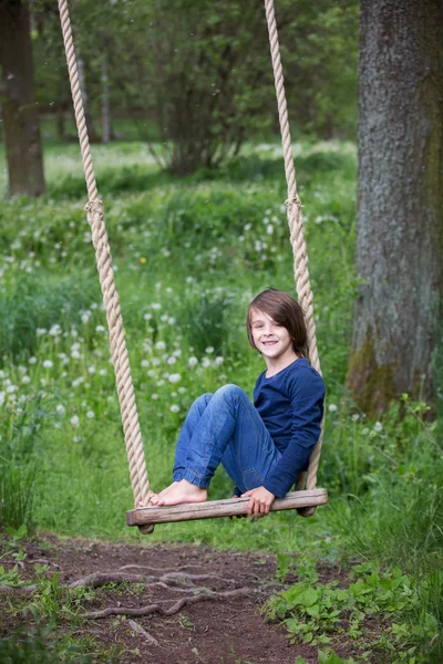 Doux enfant, garçon préadolescent, balançant sur une balançoire en bois — Photo