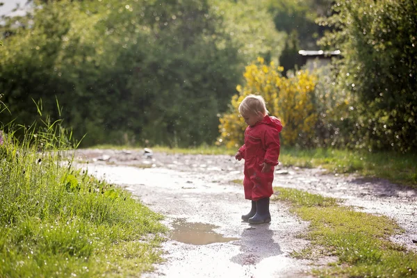 Sweet little toddler boy, blond child in red raincoat and blue b — Stock Photo, Image