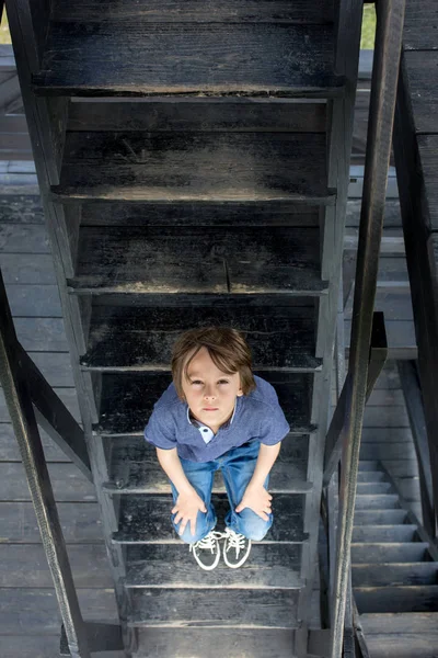 Çocuk, genç çocuk, ahşap merdivenlerde oturuyor — Stok fotoğraf
