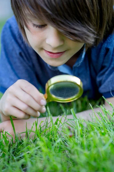 Preteen child, boy, exploring with magnifying glass, watching la — Stock Photo, Image